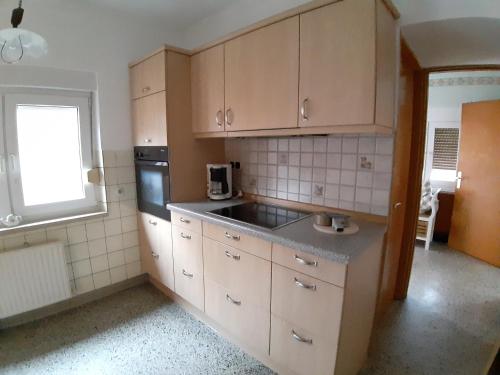 a kitchen with wooden cabinets and a sink and a window at Ferienhaus am alten Postamt in Hanerau-Hademarschen
