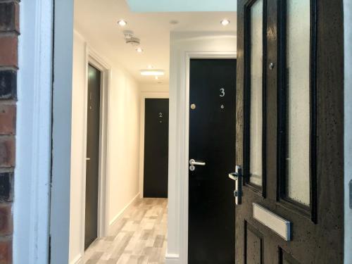 an open door to a hallway with black doors at 10min to City - FREE Parking - Private Studio - Contractor Friendly in Manchester