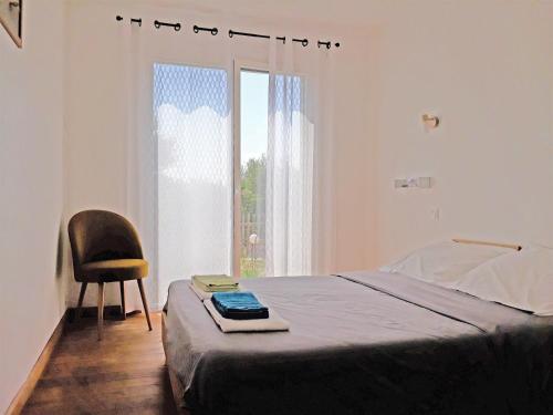 a bedroom with a bed and a chair and a window at location Phoebé dans la propriété Elaia in Tourouzelle