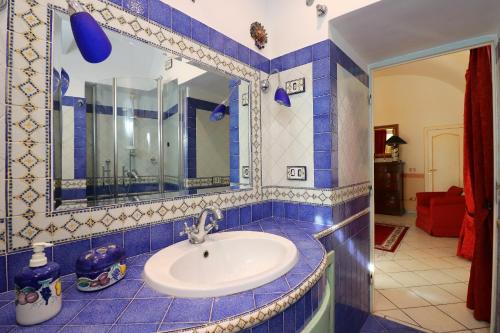 a blue tiled bathroom with a sink and a mirror at De Vivo Realty - Ilary House Positano in Positano
