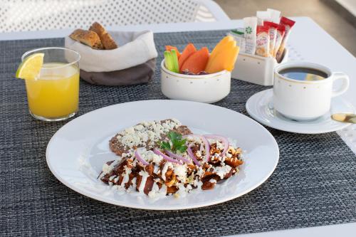 a table with a plate of food and a cup of coffee at Hotel Boutique Maria in Morelia