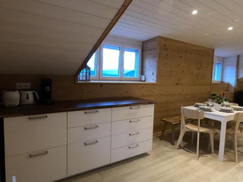 une cuisine avec une table et un comptoir blanc dans l'établissement Chez Léa et Lolo - L'Alpina, à Gérardmer