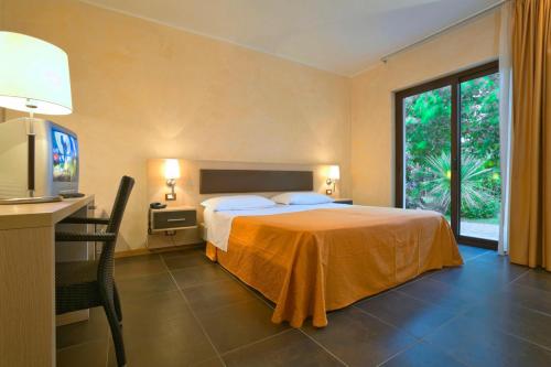 una camera d'albergo con letto, scrivania e TV di BV Borgo Del Principe a Zambrone