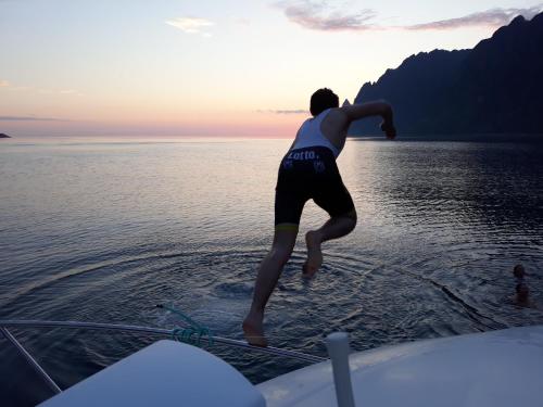 a man jumping off of a boat in the water at Skagi Bed & Lodge in Skaland