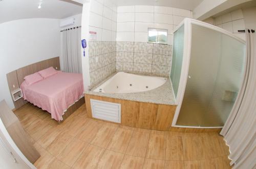 a small bathroom with a tub and a bed at Pousada Rosa in Penha