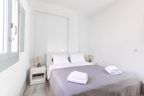 a white bedroom with a bed and a window at Phaos Santorini Suites in Imerovigli