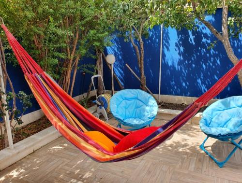 una hamaca roja con 2 sillas azules en Scala dei Turchi Beach house, en Realmonte