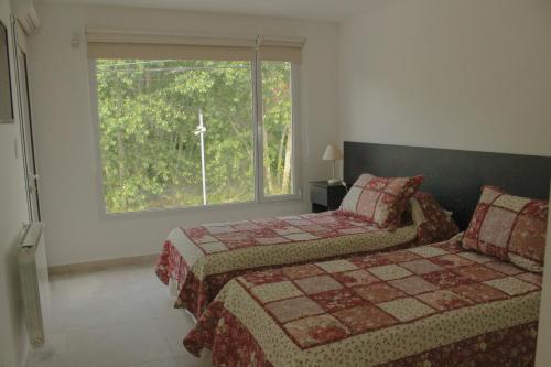 a bedroom with two beds and a large window at Descanso en Tandil in Tandil