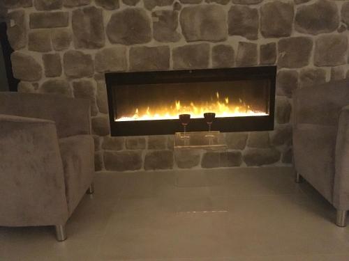 a stone fireplace with two glasses of wine at High View-A Seaside Villa With Huge Jacuzzi in Račišće