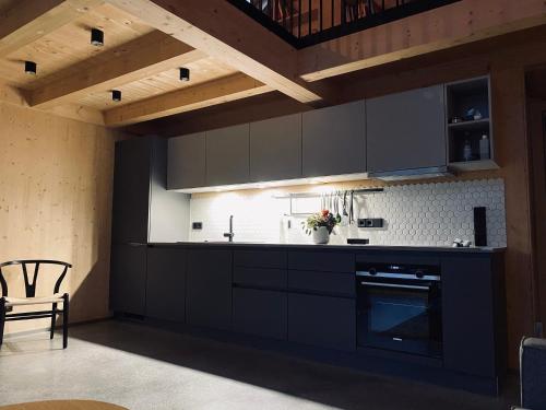 a kitchen with black cabinets and a table and a chair at Ferienhaus Königsdorf - Urlaub im Tölzer Land in Königsdorf
