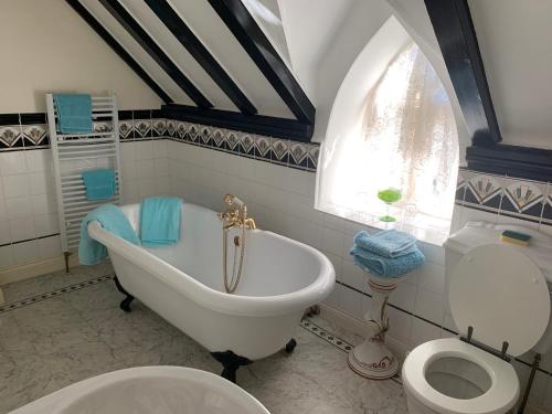 uma casa de banho com uma banheira, um WC e uma janela. em Cobweb Hall em Okehampton
