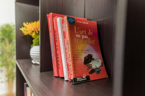 a shelf with several books sitting on a shelf at Appartement cosy à la plage - Pointe Noire in Pointe-Noire