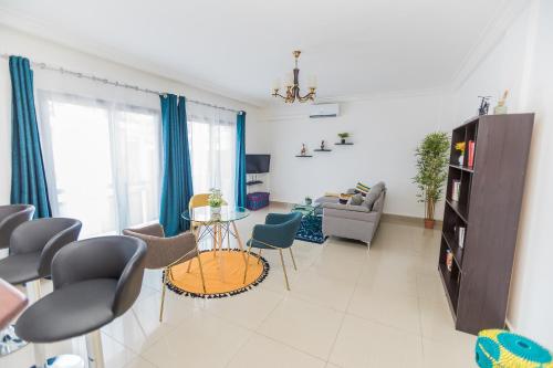 a living room with blue curtains and a table and chairs at Appartement cosy à la plage - Pointe Noire in Pointe-Noire