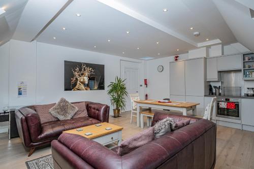 a living room with two leather couches and a table at 5 Central Chambers in Stratford-upon-Avon