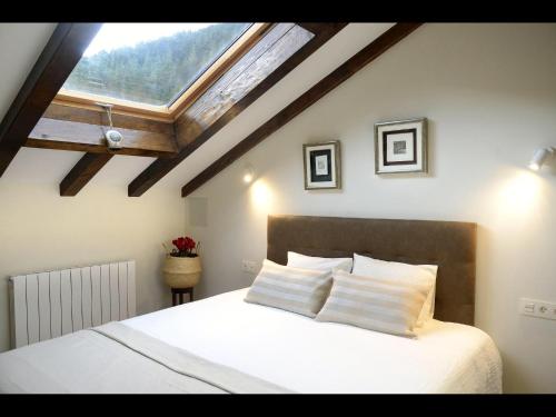 a bedroom with a large white bed with a skylight at Casa Rural Andikoetxe Landetxea in Aulestia