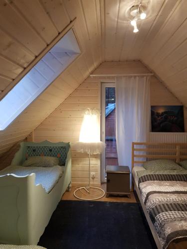 un dormitorio en el ático con 2 camas y una lámpara en Werbena&Mięta, en Serpelice