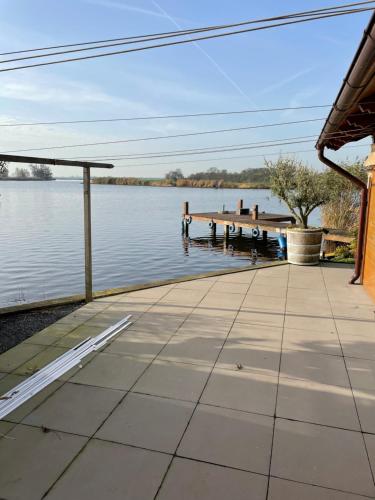 a walkway next to a lake with a dock at Vakantie huis aan het water in Rijpwetering