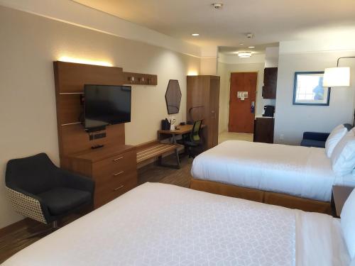 a hotel room with two beds and a flat screen tv at Holiday Inn Express & Suites Galveston West-Seawall in Galveston