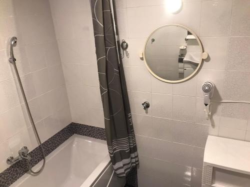 a bathroom with a shower and a tub with a mirror at Apartman Samardžić in Višegrad