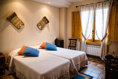 a bedroom with two beds with blue pillows at Alojamientos Rurales La Aldaba in Navalagamella