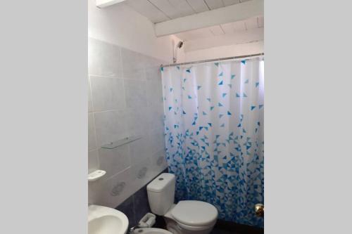 une salle de bain avec toilettes et douche avec un rideau de douche bleu dans l'établissement La posta de corumba, à La Paloma