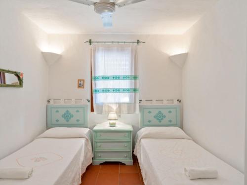 2 łóżka w małym pokoju z oknem w obiekcie Villa with a swimming pool, overlooking the crystal-clear waters of the Costa Smeralda w mieście Porto Cervo