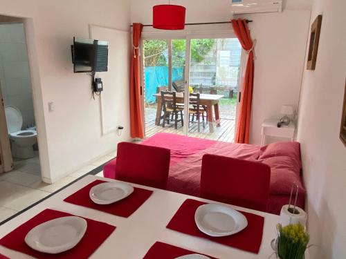 1 dormitorio con cama roja, mesa y sillas en Apartamento en Country Pilar Piscina Parrilla propia hasta 4 personas en Pilar