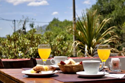 a wooden table with two glasses of orange juice and food at Portal de La Cumbre in La Cumbre