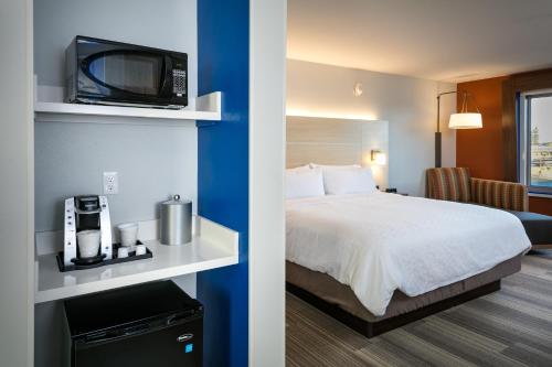 a hotel room with a bed and a tv on a shelf at Holiday Inn Express & Suites - Bend South by IHG in Bend
