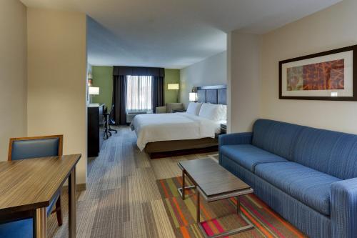 a hotel room with a bed and a couch at Holiday Inn Express Hotel & Suites Dayton-Centerville by IHG in Centerville