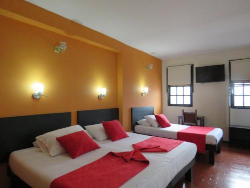 a room with two beds with red and white pillows at Hotel La Herreria Colonial in Popayan