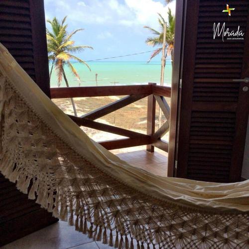 a hammock in a room with a view of the beach at Morada dos Cataventos (Frente Mar) in Barra de Camaratuba