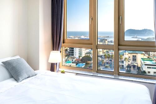 a bedroom with a white bed and a large window at Shin Shin Hotel Seogwipo in Seogwipo