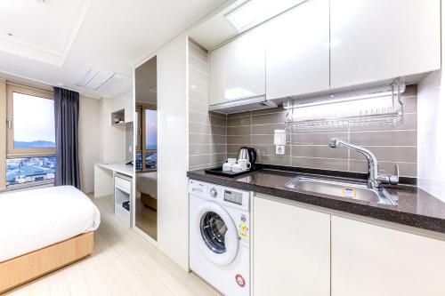 a kitchen with a sink and a washing machine at Shin Shin Hotel Seogwipo in Seogwipo