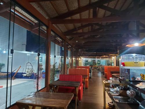 a restaurant with wooden tables and chairs and a large window at Pousada Praia Brava in Matinhos