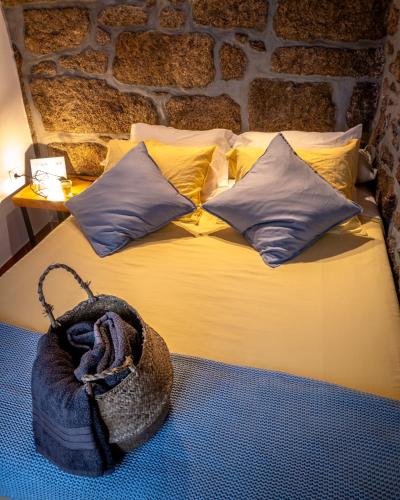 a bed with yellow pillows and a bag on it at Refúgio do Óscar in Gavieira