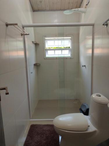 a bathroom with a shower and a toilet and a window at Casa Paúba 80m do Mar in Maresias