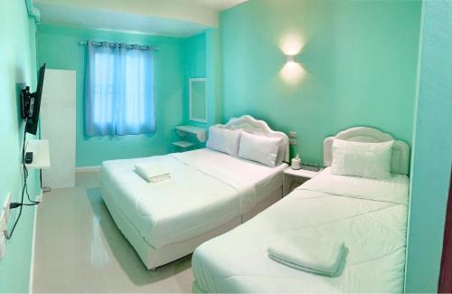 two beds in a room with blue walls at Lomluang hostel&hotel in Nan