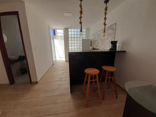 a kitchen with two bar stools and a counter at Praias Bellas Aconchegante Duplex in Pirangi do Norte