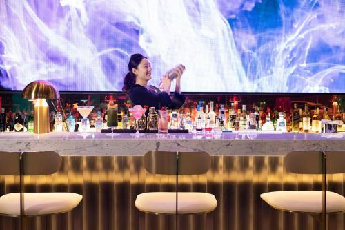 a woman standing behind a bar filled with cocktails at Mondrian Seoul Itaewon in Seoul