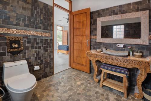a bathroom with a toilet and a sink and a mirror at Wake in Paradise Lebah Villas Pool Kitchen Spa in Ubud