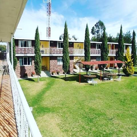 a building with a yard with tables and umbrellas at Posada Dos Hermanos in Huasca de Ocampo