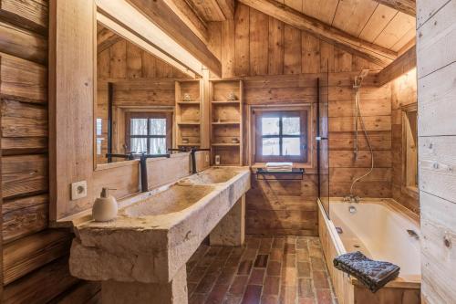 La salle de bains est pourvue d'un grand lavabo en pierre et d'une baignoire. dans l'établissement Chalet Les Meuniers, à Megève