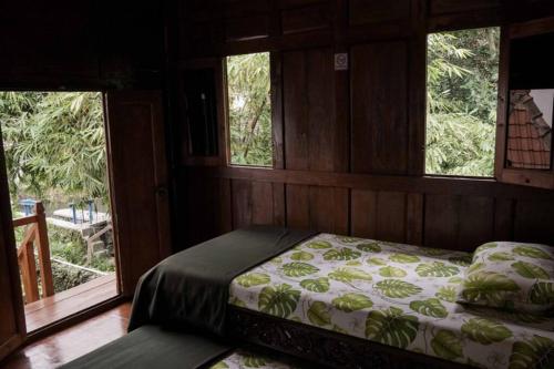 A bed or beds in a room at Rumah Kayu Joglo Yudhistira, tepi sungai, 2BR