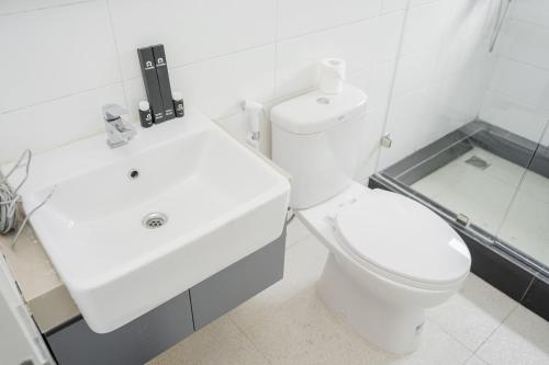 a white bathroom with a toilet and a sink at Luxurious and Spacious Apartment 2BR Tuscany Residence BSD By Travelio in Ciater-tengah