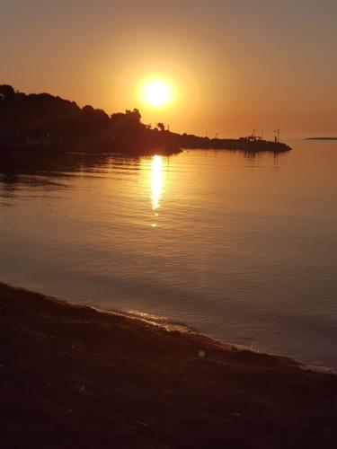 a sunset over a body of water with a beach at Eleni B&B in Limánion