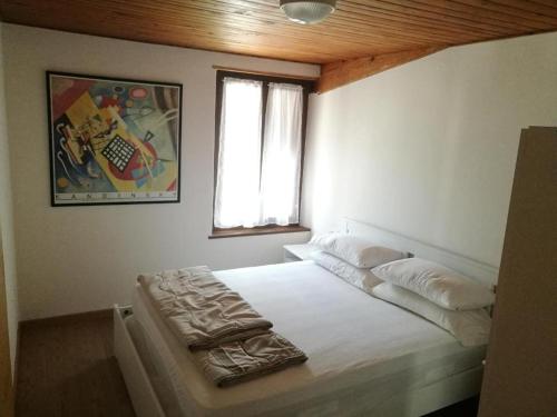 a bedroom with a white bed with a window at Casa Renzo - Dolomiti - Trentino in Mezzano