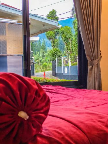a red bed with a red pillow in front of a window at AL Marina Resort in Puncak