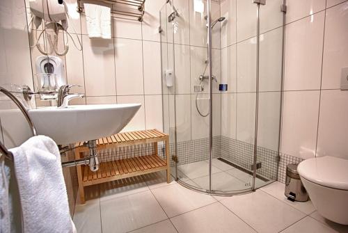 a bathroom with a shower and a sink and a toilet at Aroma Stone Hotel Spa in Syców