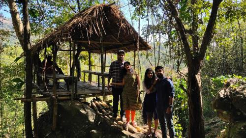 a group of people standing in front of a hut at Beyond Eco Living in Munnar